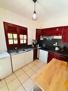 a kitchen with red cabinets and a wooden table at La Case Auvergnate in Anse-Bertrand