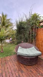 una panca di vimini appoggiata su un ponte di legno di Suite completa com área verde a Camaçari