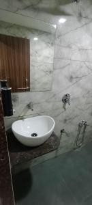 a bathroom with a white sink and a mirror at Hotel Nest View In in Ahmedabad +22 photos