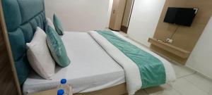 a bedroom with a large bed with green and white pillows at Hotel Nest View In in Ahmedabad