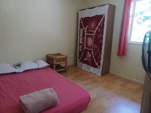 ein Schlafzimmer mit einem roten Bett und einem Fenster in der Unterkunft Fare vallée de Paopao in Paopao