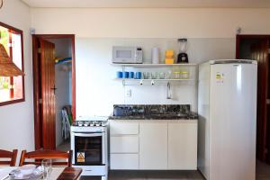 una cucina con mobili bianchi e un frigorifero bianco di Chalé Refúgio dos Corais 1 a Japaratinga Altre 16 foto