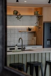 eine Küche mit einem Waschbecken und einigen schwarzen Hockern in der Unterkunft Central City Queenstown Retreat - 3 Bedroom Apartment in Queenstown