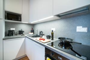 a kitchen with white cabinets and a stove top oven at New Modern Home-Projector-Nespresso-View-Balcony in Komárov