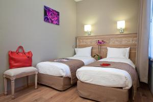 una habitación de hotel con 2 camas y un bolso rojo en una silla en Hôtel Du Printemps en París