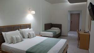 a hotel room with two beds and a desk at Thassos Hotel in Pefkari
