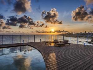 een terras met een bankje en een zwembad met zonsondergang bij Hotel Camarote Salvador in Salvador