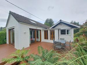 a small white house with a wooden deck at Le Châlet de l'Authie in Vitz-sur-Authie