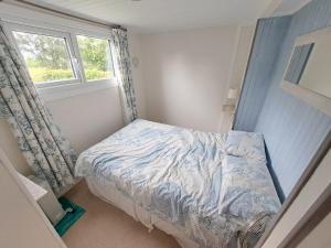 a small bedroom with a bed and a window at Le Châlet de l'Authie in Vitz-sur-Authie