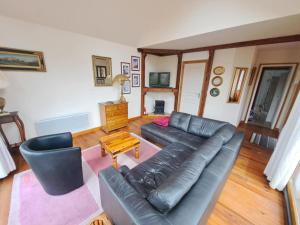 a living room with a leather couch and a table at Le Châlet de l'Authie in Vitz-sur-Authie