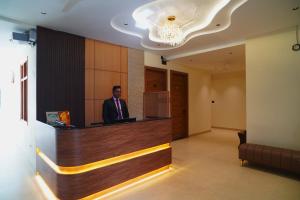 a man standing at a reception desk in a lobby at Hotel Kunadan Courtyard in Gwalior