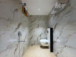 a bathroom with a toilet and a marble wall at Hotel Kunadan Courtyard in Gwalior