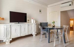 ein Esszimmer mit einem Tisch und einem TV auf einem weißen Schrank in der Unterkunft Spàzio apartments Sangiuliano in Catania