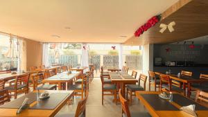 een restaurant met houten tafels en stoelen en ramen bij W Tambaú Apart Hotel in João Pessoa