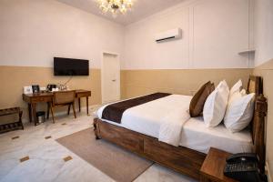 a bedroom with a bed and a desk and a television at Victoria Mansion - A Signature Collection by HST Hotels in Udaipur