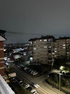 una strada cittadina con auto parcheggiate e edifici di notte di Bleon Apartment a Prizren