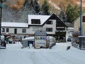 a snow covered street in front of a house at Pension Camping Schausten in Cochem