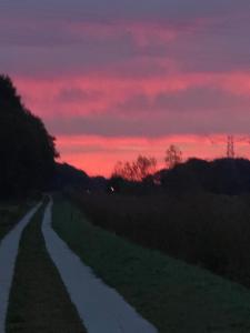 een onverharde weg bij zonsondergang met een rode lucht bij Huize Kroezzz in Goor