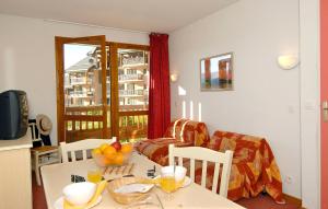 a living room with a table and chairs and a room with a window at Résidence Odalys Les Lumières de Neige in Valmeinier