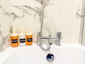 a bathroom sink with two bottles of soap and a faucet at Comfortable 3-Bed House near Canterbury Centre in Canterbury +30 photos