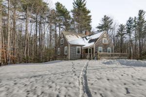 a house in the snow with footprints at Charming Jaffrey Cottage with Deck and Grill! in Jaffrey