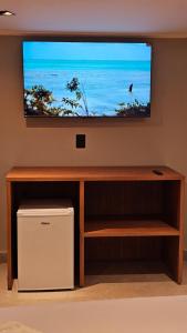 - une télévision à écran plat au-dessus d'un centre de divertissement en bois dans l'établissement Chalés Feliz Boipeba, à Cairu