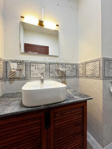 a bathroom with a white sink and a mirror at Haven Mushkpuri Terraces Khaira Gali - 3BR Home, Lawn, BBQ & Fireplace in Chhāngla Gali