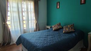 ein blaues Schlafzimmer mit einem Bett und einem Fenster in der Unterkunft Casa a 500 metros del Mar in Quequén