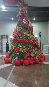 a christmas tree in a mall with a person standing next to it at Quarto suite in Florianópolis