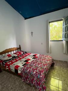 a bedroom with a bed with a comforter and a window at CANTINHO do SILENCIO in Morro de São Paulo