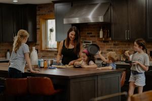 una donna in cucina con tre bambini in piedi intorno di Compass Retreat for large groups a Buchanan