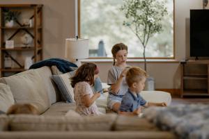 tre bambini seduti su un divano in un soggiorno di Compass Retreat for large groups a Buchanan Altre 102 foto