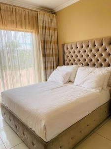 een slaapkamer met een groot bed met een groot raam bij Loreho boutique in Mahikeng