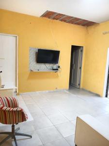 een woonkamer met een tv aan een gele muur bij Aluguel de Casa de Férias in Santa Branca
