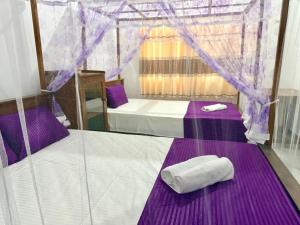 two beds in a tent with purple sheets and towels at Midigama Lucky Villa in Midigama East