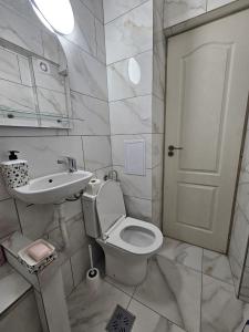 un bagno bianco con un water e un lavandino di BOMBA Apartman a Târgu Secuiesc