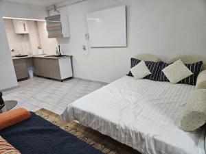 a bedroom with a large bed and a kitchen at BOMBA Apartman in Târgu Secuiesc