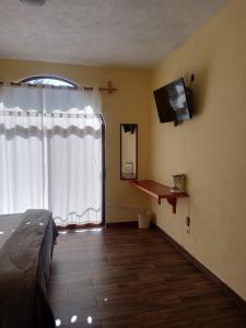 een slaapkamer met een bed en een flatscreen-tv bij HOTEL RESTAURANT LOS PRISMAS in Huasca de Ocampo