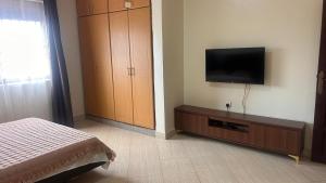 een slaapkamer met een bed en een flatscreen-tv bij Pure Haven in Mbale +16 foto's