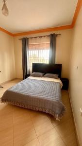 een groot bed in een slaapkamer met een raam bij Pure Haven in Mbale