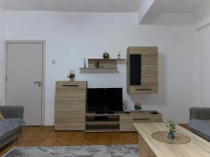 un soggiorno con TV su un centro di intrattenimento in legno di Bleon Apartment a Prizren