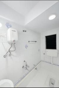 a white bathroom with a toilet and a bath tub at Family Home 2BHK Apartment Thane West in Thane