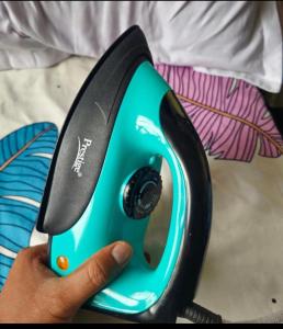 a hand is holding a blue and black iron at Family Home 2BHK Apartment Thane West in Thane +3 photos