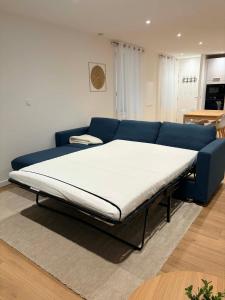 een bed in een woonkamer met een blauwe bank bij L élégance centre historique Dole 70 m2 in Dole