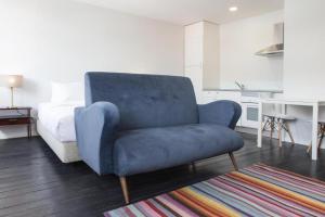 a blue chair in a living room with a bed at Porto República Suites in Porto