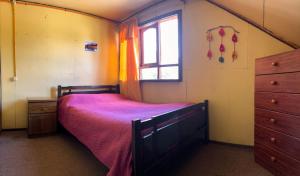 ein Schlafzimmer mit einem Bett, einem Fenster und einer Kommode in der Unterkunft Hospedaje La Cascada in Futaleufú