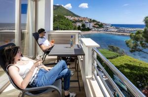 two people sitting at a table on a balcony with wine glasses at Blue Bay rooms in Cala Gonone +36 photos