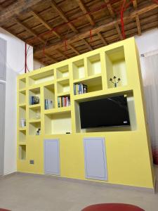 L'Abbraccio في تيفولي: جدار أصفر اللون مع تلفاز في غرفة +20 صورة