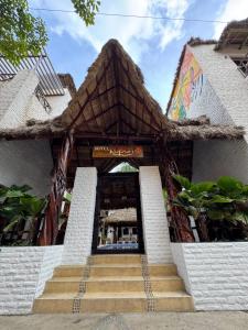 een gebouw met een rieten dak en een trap aan de voorkant bij Hotel Kupuri in Sayulita