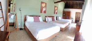 een slaapkamer met 3 bedden met witte lakens en roze kussens bij Hotel Kupuri in Sayulita